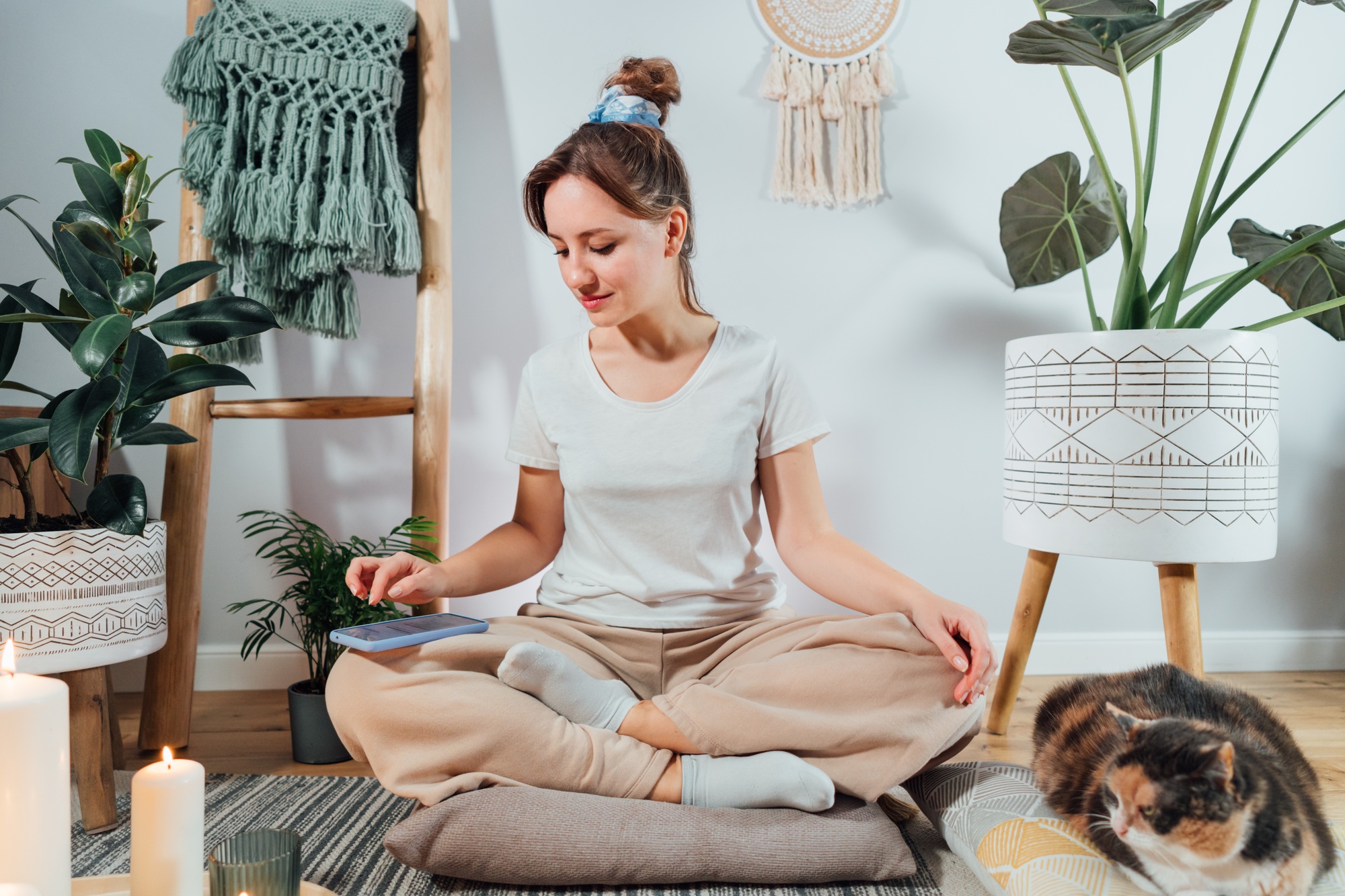 Young healthy woman using phone for setting mobile app for meditation at home